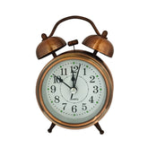 A vintage-style brass alarm desk clock with a white face, black hands, and a brass stand, featuring a traditional design with a twin bell alarm.